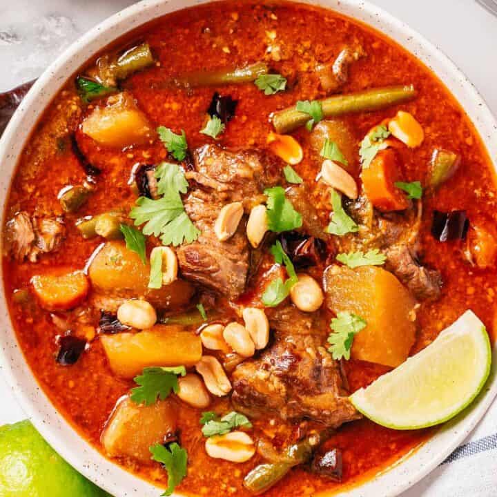 massaman beef curry with garnishes in a bowl ready for serving