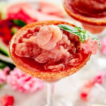 watermelon margarita in a margarita glass served with watermelon star shaped slice and basil leaves