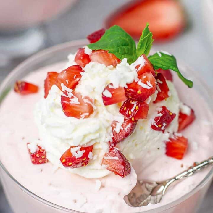 Strawberry Mousse in a glass cup with whipped cream and strawberries closeup shot