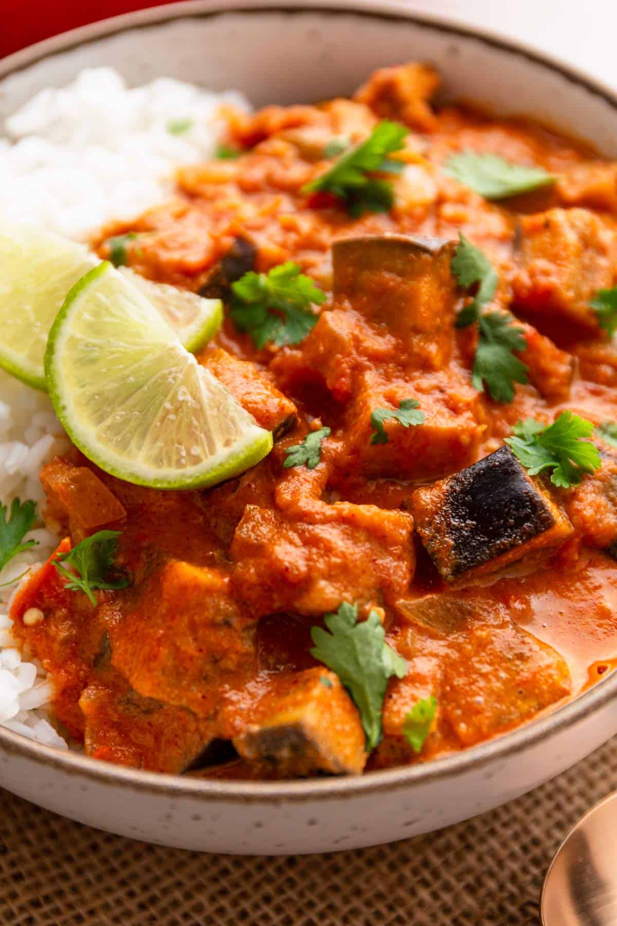 eggplant curry bowl served with rice and limes.