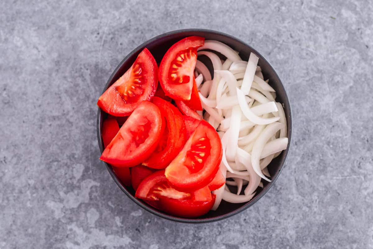 Tomato and Onion Salad with herbs in a black bowl