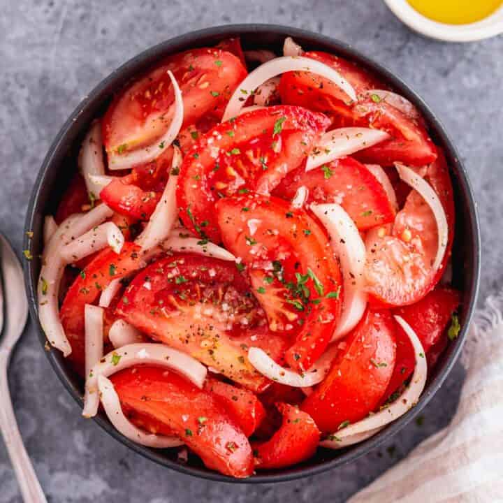 Tomato and Onion Salad with herbs in a black bowl