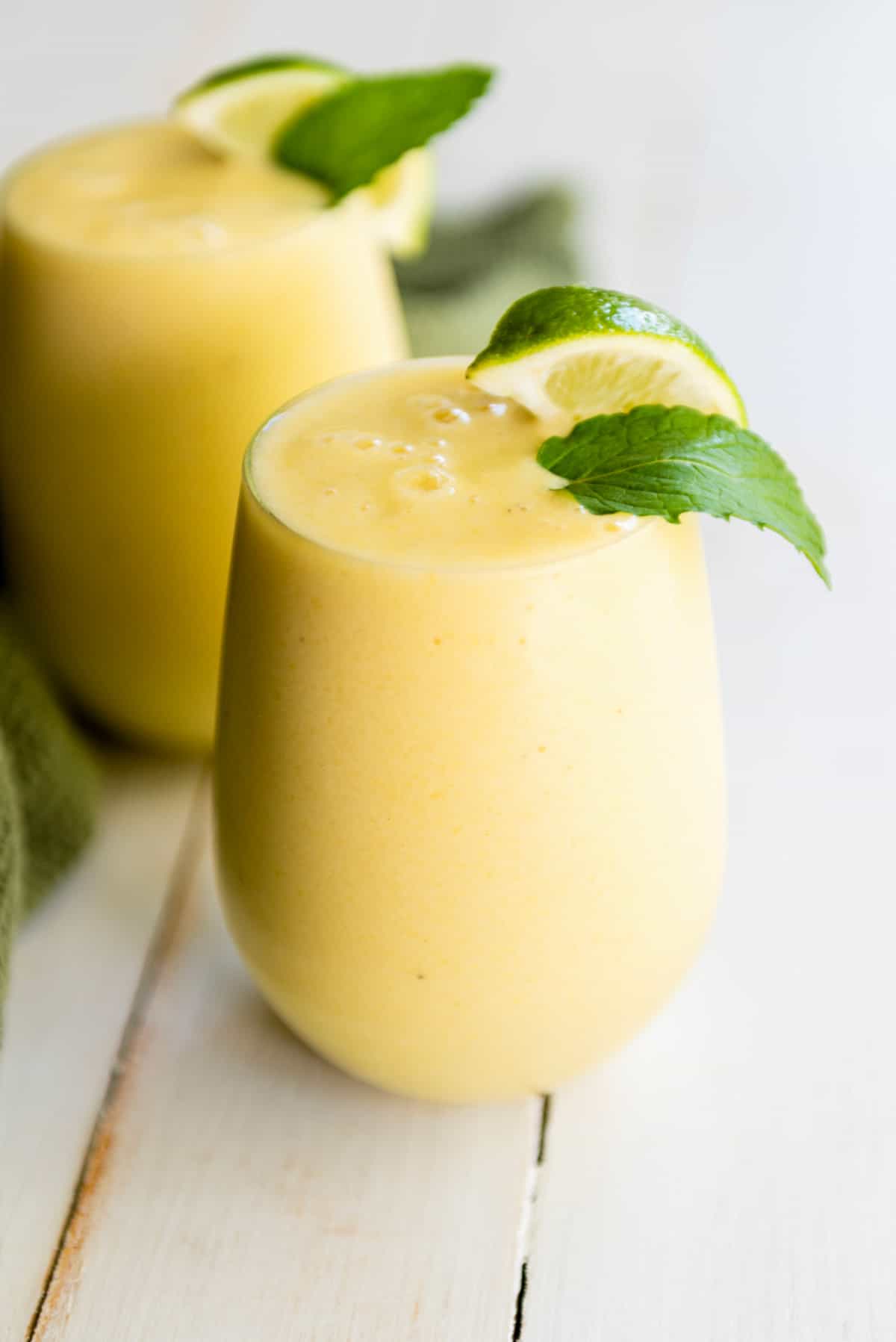 tropical smoothie in a tall glass with mint and lime wedge