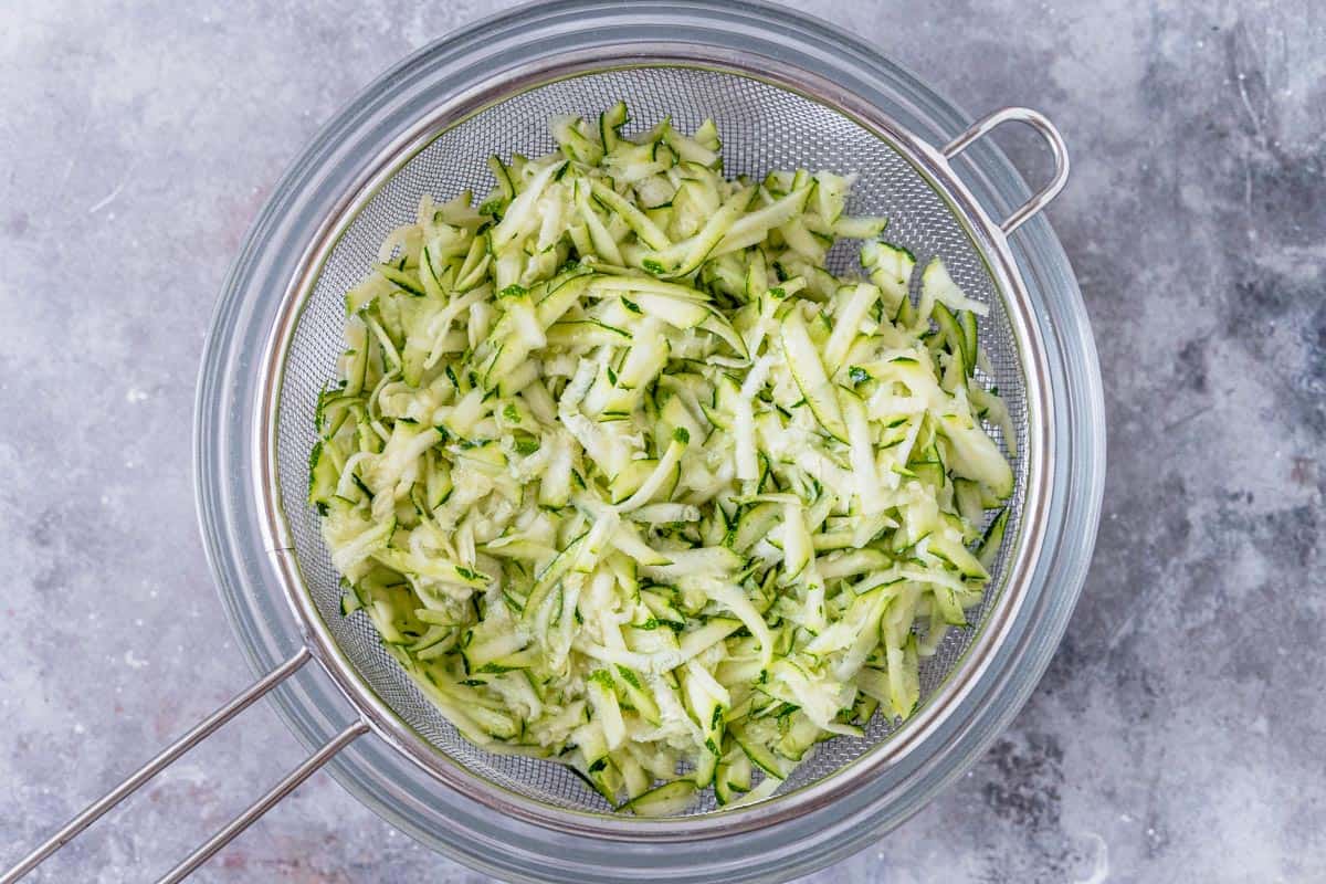 grated zucchini in a strainer and pot